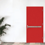 Pintu baja minimalis berwarna merah dengan handle panic bar modern di antara tanaman hias.