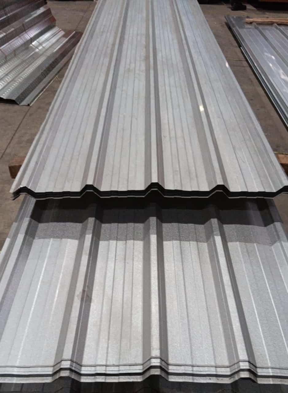 Tumpukan lembaran atap spandek galvalum profil trimdek untuk konstruksi bangunan industri.